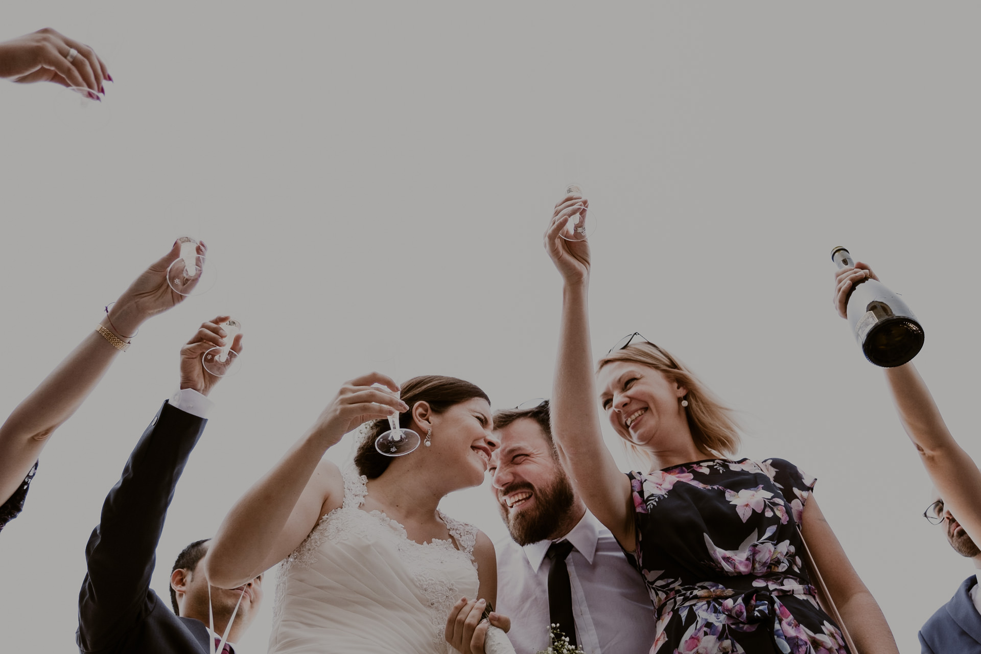 noivo e noiva brindam no seu casamento com convidados à volta